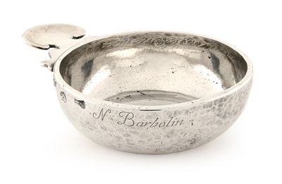 un bol en argent contenant une cuillère sur une surface blanche