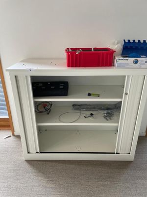 a white cabinet with a red bin on top of it