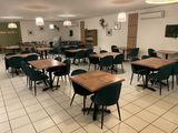 de nombreuses tables et chaises dans une pièce au sol carrelé de blanc