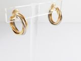 a pair of gold and silver hoop earrings on a clear acrylic stand