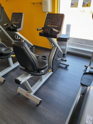 une salle de sport équipée d'une rangée de vélos d'appartement et de tapis de course