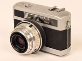 a silver and black camera on a white surface