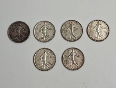 six types différents de pièces d'argent sur une surface blanche