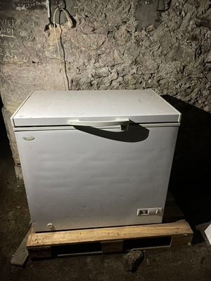 un petit réfrigérateur blanc posé sur une palette dans une pièce