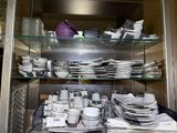 many plates and bowls on the shelves in the kitchen