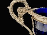 a blue glass cup with a gold handle on a black background