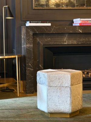 a white ottoman sitting in front of a fireplace in a living room