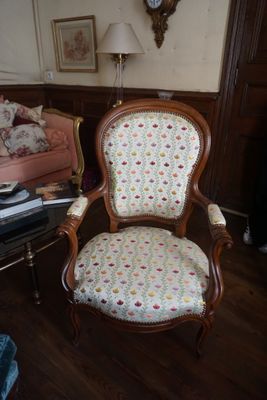 une chaise qui se trouve dans un salon où il y a une horloge accrochée au mur