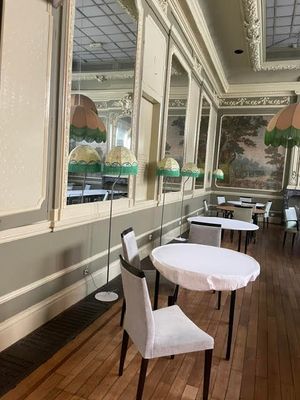 Des tables et des chaises sont disposées dans une pièce où est accroché un tableau au mur.