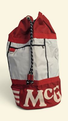 red and white backpack with the word mcq on it sitting on a white surface