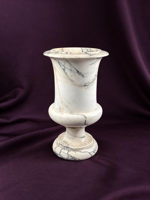 marble vase sitting on a purple cloth with a purple background