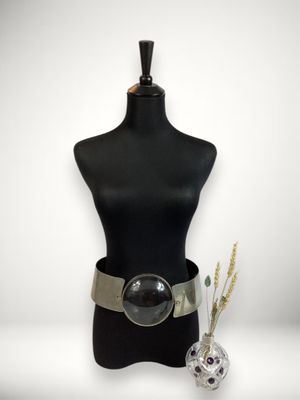 un mannequin noir avec une ceinture argentée et un vase rempli de fleurs