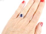 a woman ' s hand holding a ring with a blue stone