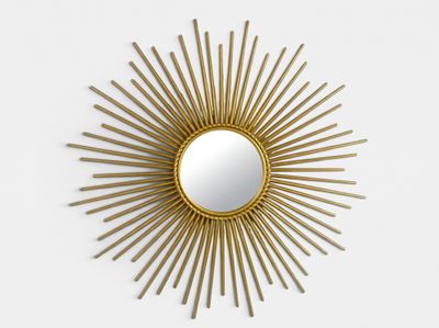 a close up of a gold sunburst mirror on a white wall