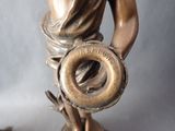 a bronze statue of a woman holding a donut