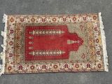 un tapis rouge posé à même le sol, orné de franges
