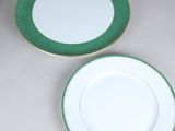 two green and white plates with gold rims on a table