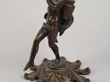 une figurine antique en bronze représentant un homme tenant un éventail