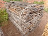 une pile de bois posée par terre devant un mur de briques
