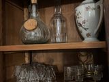 bottles and glasses on a wooden shelf in a cabinet