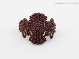 a close up of a red beaded ring on a white surface