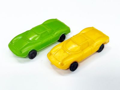 des petites voitures en plastique jaunes et vertes posées sur une surface blanche
