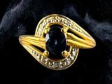 a close up of a gold ring with a black stone
