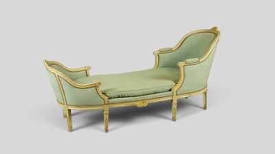 a green chaise with a gold frame and a green cushion