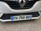 the front of a white car with a blue license plate on it