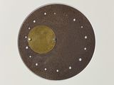 a brown plate with a gold disc on it
