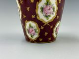 un gros plan d'un vase rouge avec des fleurs roses