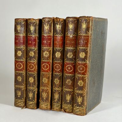 three old books sitting on top of each other on a white surface