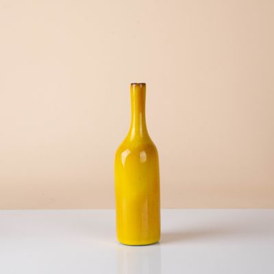 yellow glass bottle on a white table against a beige background