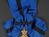 a close up of a blue ribbon with a gold cross on it