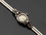 une montre-bracelet pour femme sertie de diamants, attachée à une chaîne