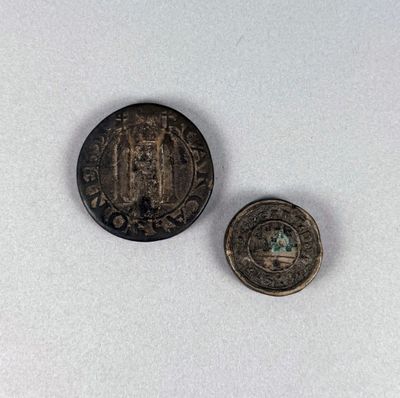 an old coin and a small coin sitting on top of a white surface