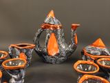 a group of orange and black teapots and cups on a table