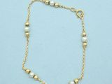 a gold chain bracelet with pearls on a blue background