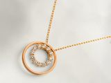 un collier plaqué or orné d'un pendentif en forme de cercle au centre duquel est serti un diamant