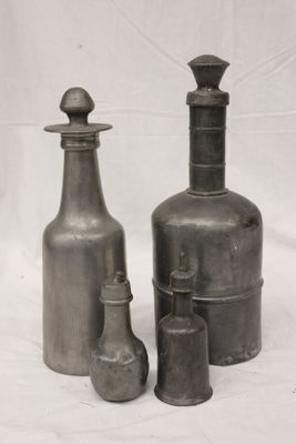 trois bouteilles et un vase posés sur une surface blanche