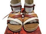 une paire de sandales marron et blanches posée sur une boîte rouge