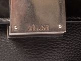 the back of a black purse with a metal tag on it