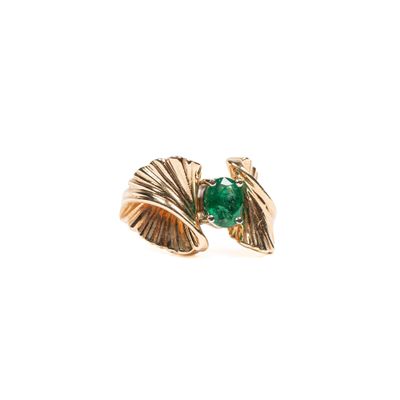 gros plan d'une bague en or avec une pierre verte
