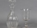 a glass bottle and a glass goblet sitting next to each other