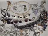 many different types of necklaces and bracelets on the table