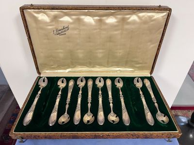 six cuillères en argent dans un coffret posé sur une table
