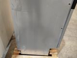 a silver dishwasher sitting on a pallet in a warehouse