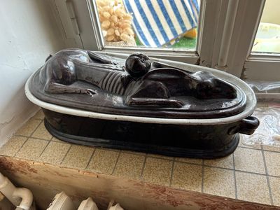 une statue représentant un homme allongé dans un bateau posé sur une table