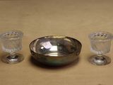 un bol en argent et deux verres posés sur une table
