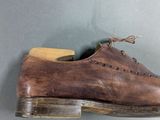 an old pair of brown shoes hanging on a wall